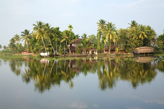 Reflection in river water of tropic palms and houseboat