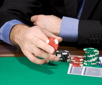 Hand of man holding casino chip over green felt
