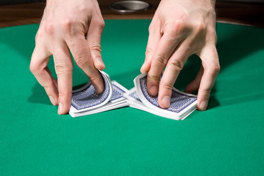 Dealer shuffle cards in casino over green felt