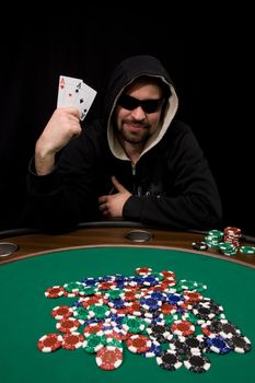 Man shows two aces and win hand in poker casino with chips on green felt