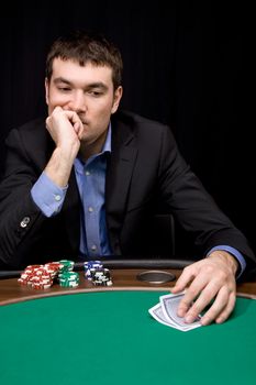 Stylish man in black suit thinking before bet in the casino