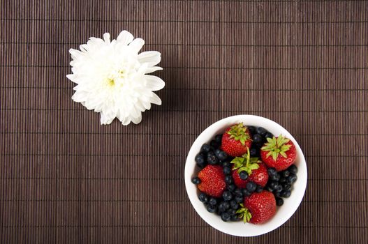 light Breakfast: flower and Berries on a table on a bamboo background