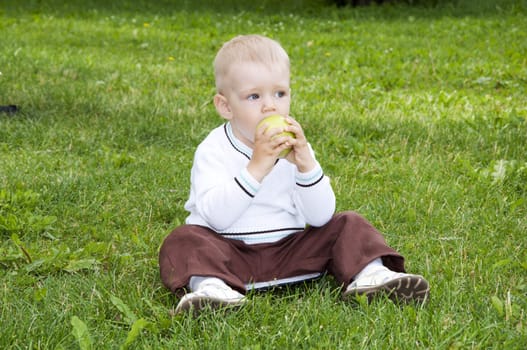 Portrait of a preteen boy with a apple in his hand and green grass in the background
