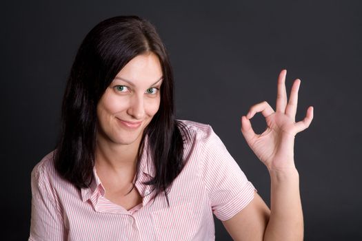 Smling girl showing ok sign with fingers over gray