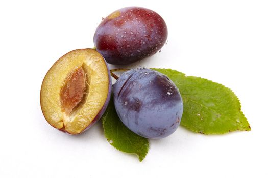 Whole plum and halves isolated on the white background