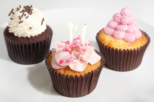Various cupcakes decorated with frosting and dragees
