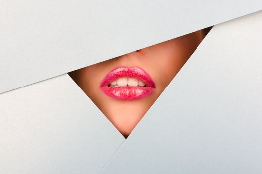 Beautiful female lips closeup behind silver paper background