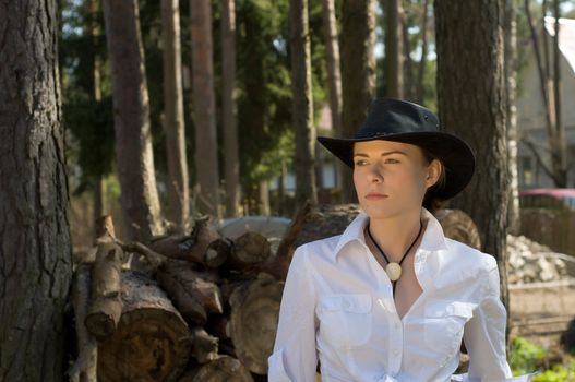 Portrait of a woman in a white shirt and cowboy hat on a ranch.