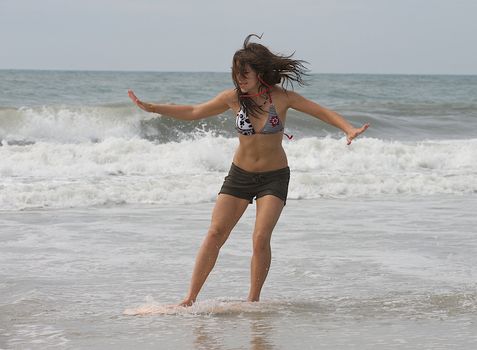 Athletic teen girl skim boarding in the surf of the Atlantic Ocean in Emerald Isle, North Carolina. 