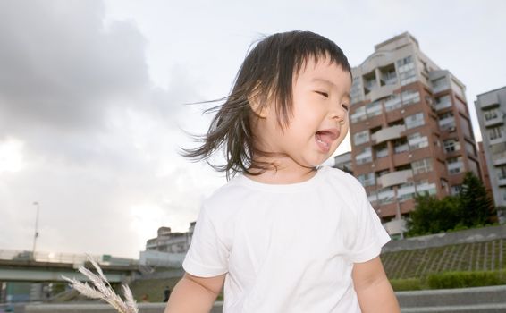 She is an East Asian gabby baby in front of apartment in the outdoor.