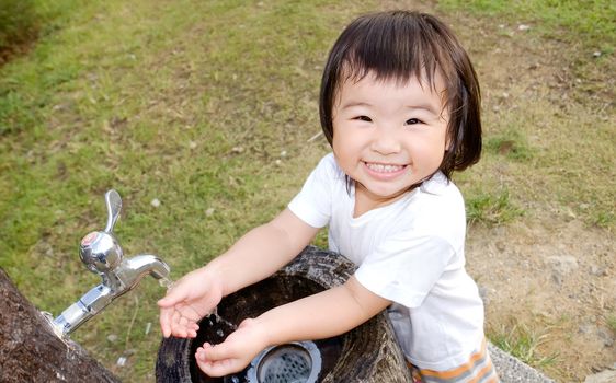 She is a happy baby washing her hand in the outdoor.