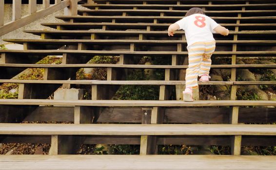 There is a baby walking in the wooden stair.