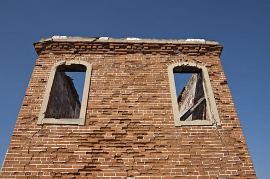 Ruins of a tower with brick walls against a blue clear sky