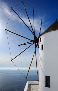 Image shows a large windmill, on the Greek island of Santorini, overlooking the Aegean Sea