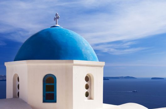 A church with a blue dome overlooks the spectacular caldera surrounding the beautiful island of Santorini, Greece