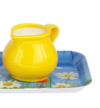 yellow pitcher with milk on tray isolated 