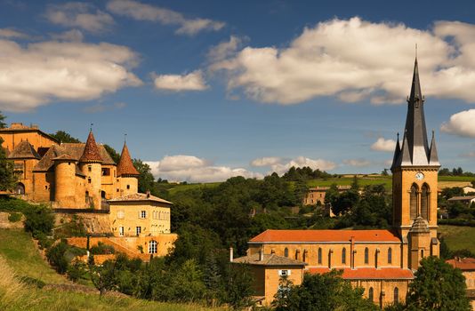 Image shows an old chateau and a church in a village in the famous wine making region of Beaujolais, France