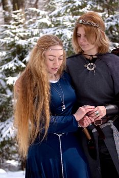 Two ladies in medieval dresses in winter forest
