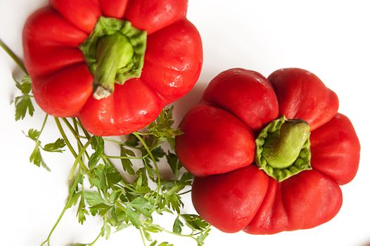 Some red peppers and greens over white