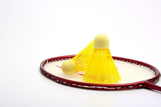 Yellow shuttlecock for badminton and a racket.