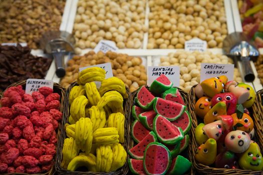 Colorful marzipan sweets in the market with dried fruits background.