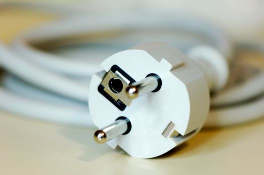 Close-up shot of a european plug connected to a long cable and photographed with shallow depth of field