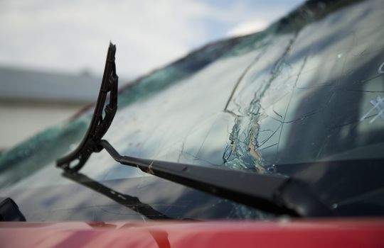 Broken windshield wiper on a cracked and broken car window