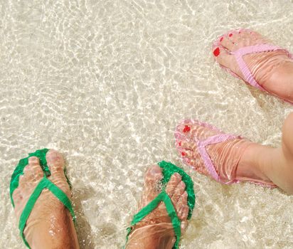 close up of feet and flip flops on a translucent ocean water