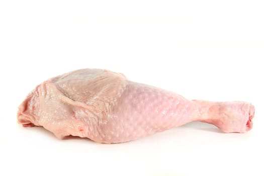 a raw chicken leg in front of white background