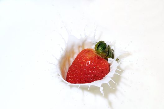 Fresh strawberry dropped into milk with a splash