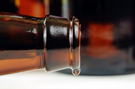 Closeup of a beer bottle with focus on the last drop hanging