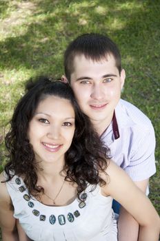 couple embraces in park, green grass background