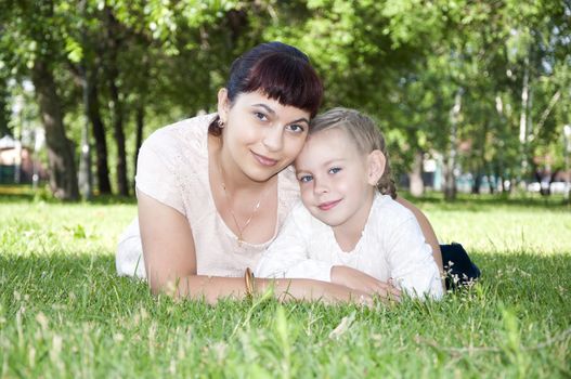 The portrait of the baby and mother in the park, on the green grass