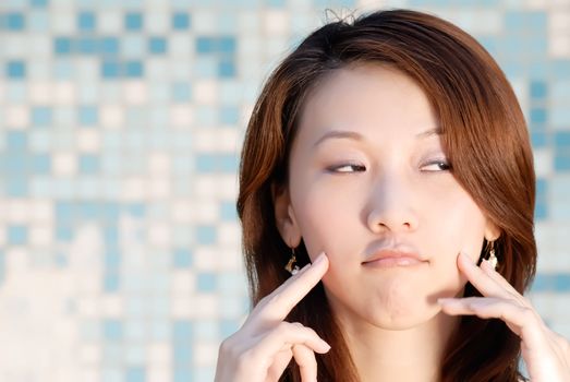 Here is a beautiful Asian lady in front of mosaic with funny face.