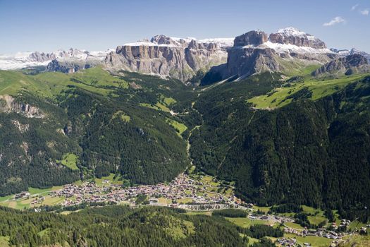 Aerial view of Canazei and Fassa valley with Saas Pordoi mount (Sella group), Pordoi pass and Sella pass