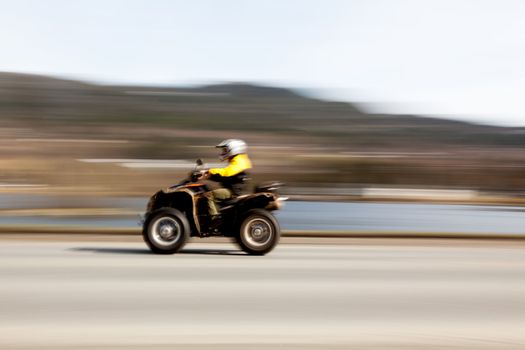 A quad on a road with motion blur