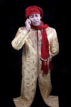 A metaphorical photo of a genie talking on the cellphone, on black studio background.
