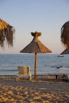 black sea beach with palms, umbrella and chairs