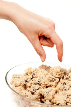 A hand reaching for a bowl of raw cookie dough