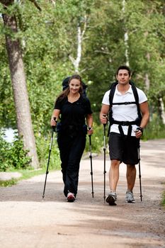 A male and female camping in the woods walking on a path