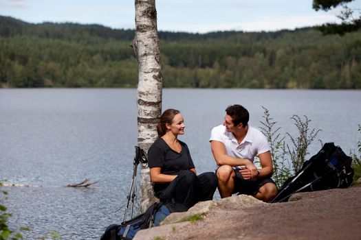 A man and woman taking a break while on a camping hike