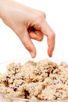 A hand reaching for a bowl of raw cookie dough