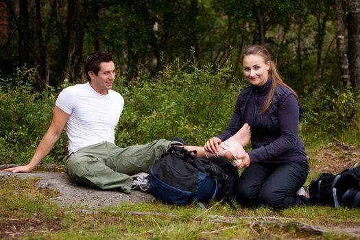 A couple camping and putting on a leg bandage