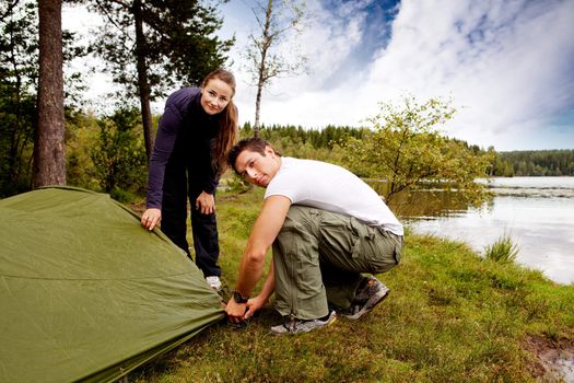 A man and woman camping - setting up a tent