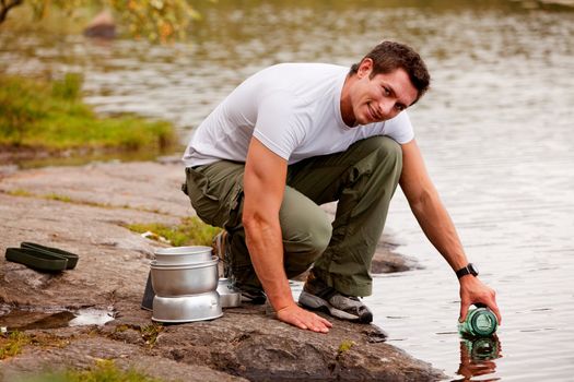 A young male adult fetching fresh water from a forest lake