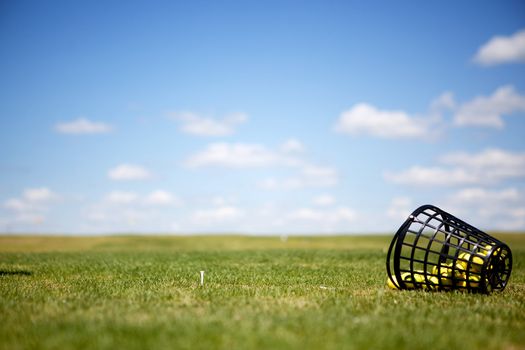 A tee and yellow golf balls on a driving range