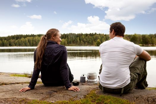 A man and woman happy camping in the forest by a lake