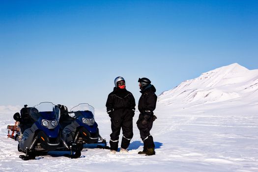 A group on a winter snowmobile adventure over a barren winter landscape