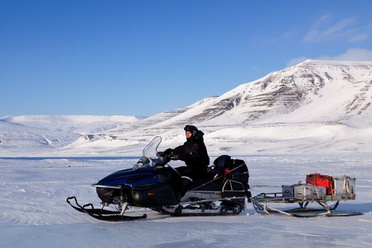 A man on a snowmobile against a winter landscape