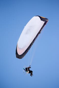 A paraglider isolated against a deep blue sky